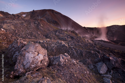 View of rugged volcanic landscape with steaming vents and colorful mountains under a pastel sky, a symphony of earth and sky, Landmannalaugar, Rangárping ytra, Iceland.