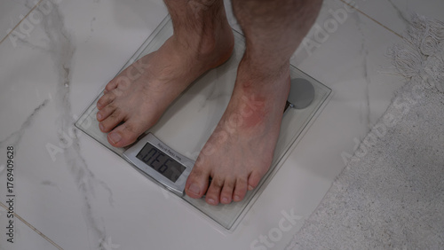 Man standing on digital scale at home measuring body weight
