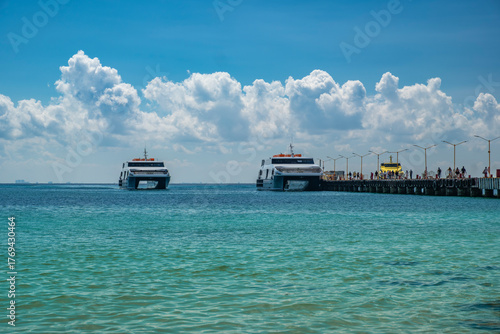 Tourist ferries to Cozumel Island docked at Playa del Carmen city pier, awaiting passengers to board, sunny day, blue sky. South destination, travel concept.