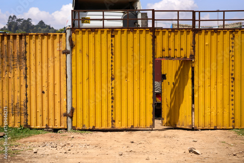 Kiambu County, Kenya - October 13th 2025 - Yellow metal fence container