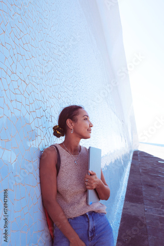 Young woman smiling holding laptop standing outdoors