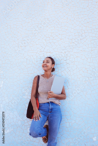 Smiling woman holding laptop looking towards future