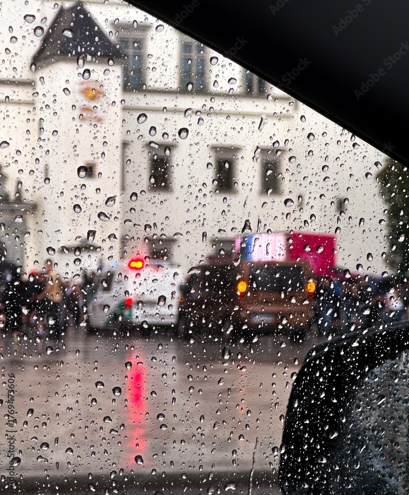 Obraz premium View through a car window. Rainy day in the city. Blurred street scene with vehicles, people, and flashing lights in the background, creating cinematic atmosphere.
