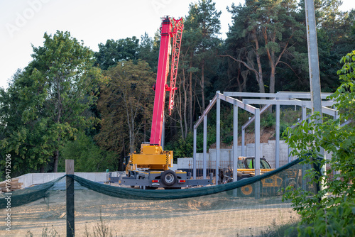 Canvas Print Truck crane and a telescopic handler in a fenced area of a construction site after work