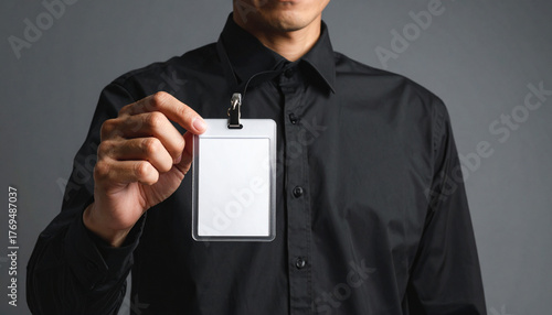 Wallpaper Mural Businessman wearing black shirt holding blank ID badge, professional corporate presentation, confident expression, close up, gray background, office concept Torontodigital.ca