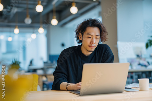 オフィスでノートパソコンを使って仕事をする若い男性