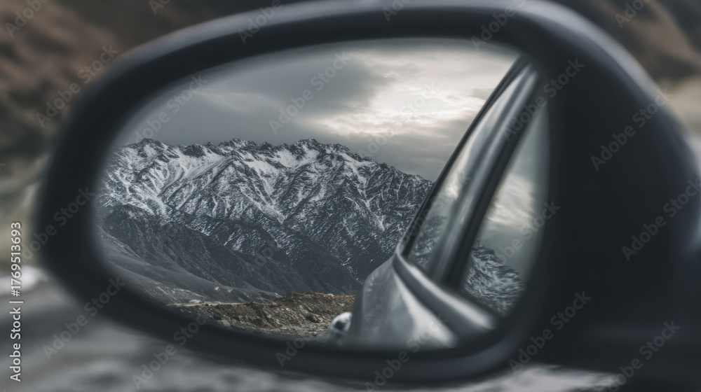 Fototapeta premium reflection in car mirror showing mountain landscape and cloudy sky, concept of journey and freedom, sharp detail, realistic texture