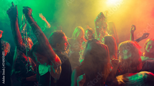 Canvas Print New Year party illuminated by green and amber light with cheerful movement