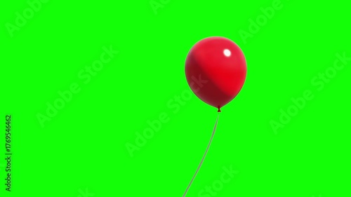 One red balloon hang in the air against a green background.