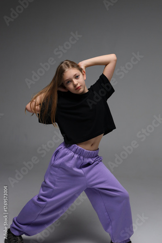 Young caucasian girl in black top and purple pants posing confidently