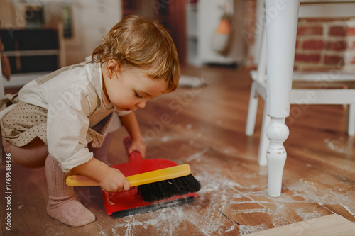 Photos Little girl cleaning up flour mess in kitchen.