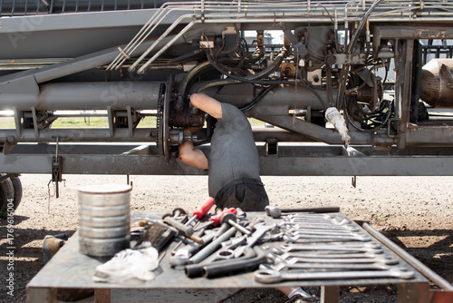 Hombre reparando maquinaria agrícola con herramientas en primer plano