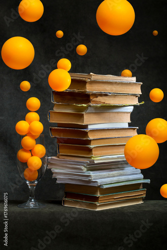 Still life with a stack of books and orange balloons