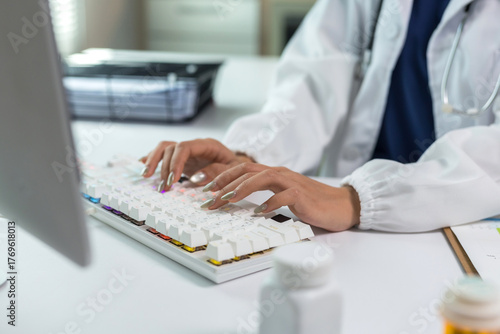 Doctor hands typing on a glowing computer keyboard, managing patient data and electronic health records in a medical office