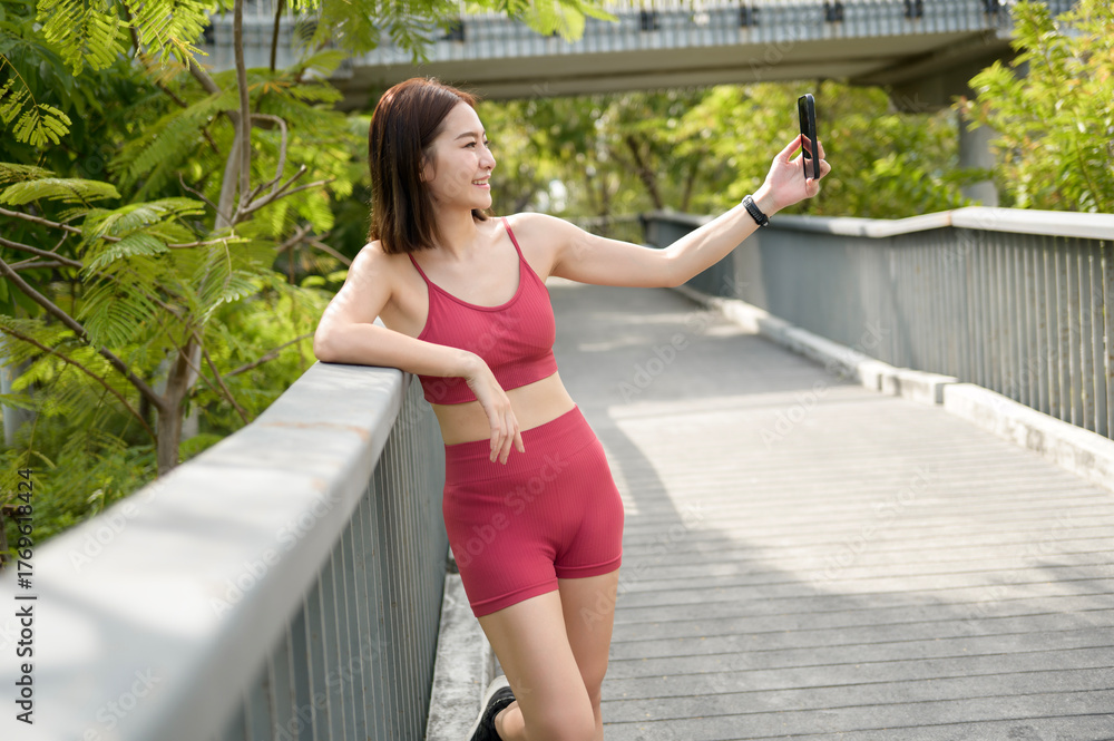Obraz premium Young Woman Enjoying a Sunny Day While Taking Selfies on a Park Walkway