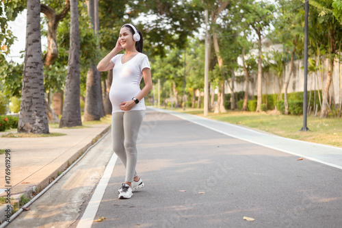 Expecting Mother Enjoying Peaceful  in Park Wearing Headphones on Sunny Day