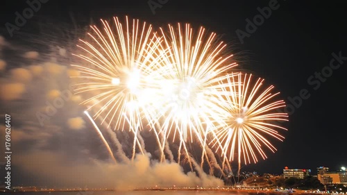 Spectacular night sky fireworks display over city skyline reflecting on water creating a
