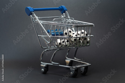 Metal shopping cart filled with mini soccer balls on a dark background