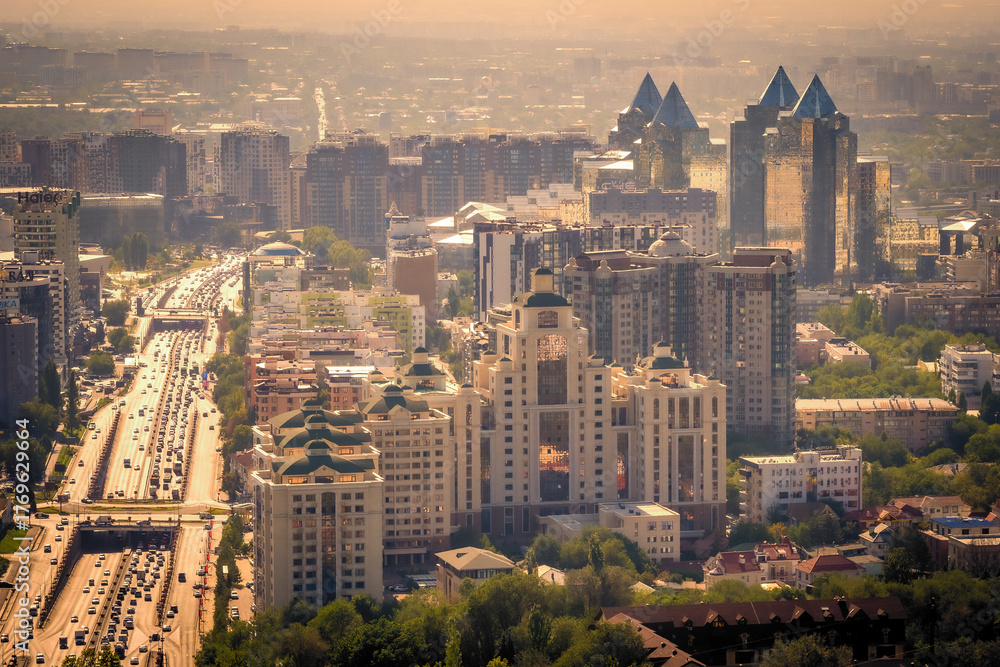 Fototapeta premium Scenic view of Almaty, Kazakhstan, as seen from Kok-Tobe Mountain at sunset, with its futuristic skyscrapers reflecting in the evening sun
