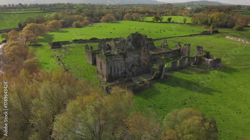 Majestic ruins emerge from lush green landscape under a bright sky in tranquil countryside
