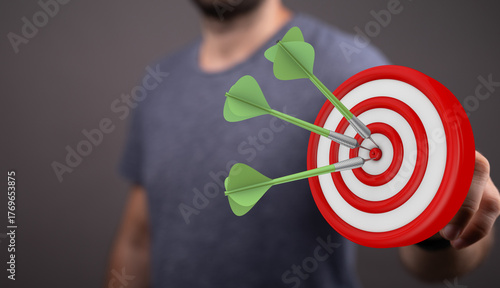 Foto A close-up shot of a man holding a dartboard with three darts hitting the bullseye, symbolizing success and achievement