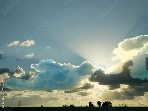 Dramatic sky with sun rays shining through clouds at sunset