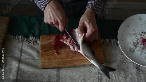 A man guts a sea bass fish with a knife