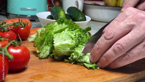 Slicing green salad into large pieces on a wooden board. Slow motion.