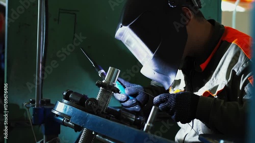 Precise welding process, operator performs detailed metal welding task