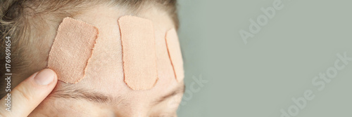 Fototapete Female adult with bandages on forehead in close-up view, skin care or injury concept