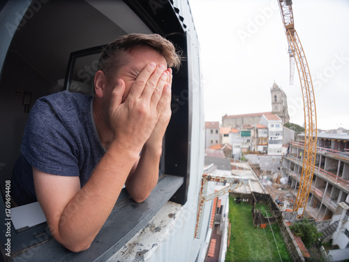 Konstfotografi Man angrily staring at a noisy construction site outside his apartment window