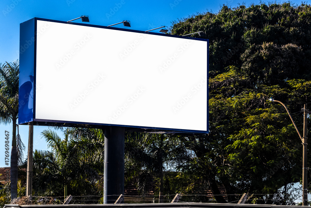 Fototapeta premium Blank billboard mockup against blue sky and trees in Brazil. Ideal for advertising, marketing concepts.