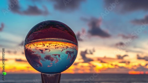 Beautiful time lapse of twilight colors reflected inside a crystal sphere resting on driftwood by the sea where evening light transforms into magic and the world turns upside down in grace.