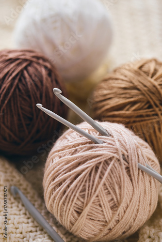 Crochet hooks and balls of beige and brown yarn on white knitted background. Knitting, crocheting supplies.