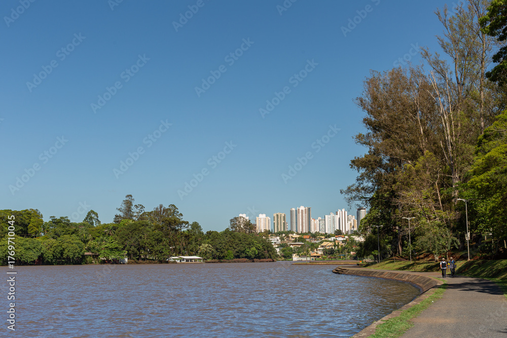 Obraz premium Orla do Lago Igapó em Londrina com caminho de pedestres e skyline ao fundo
