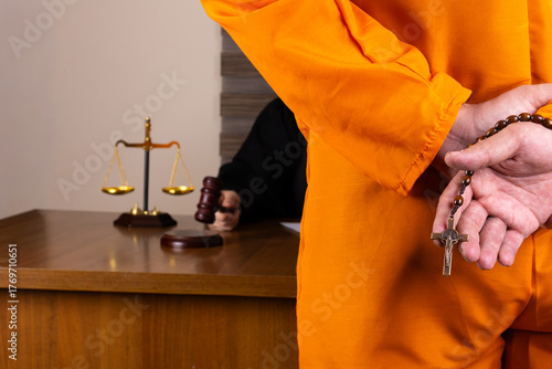 A defendant, with hands cuffed and holding a rosary, stands in a courtroom 
