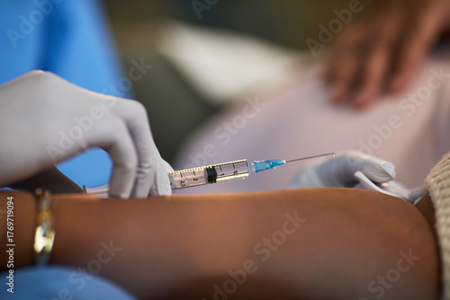 Photos Female patient receiving arm injection from gloved medical professional, close u