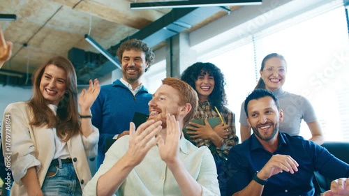 Group of cheerful men and women laughing and clapping in office. Team celebrating success and enjoying good moment together after presentation. Happy colleagues smiling at workplace indoors.