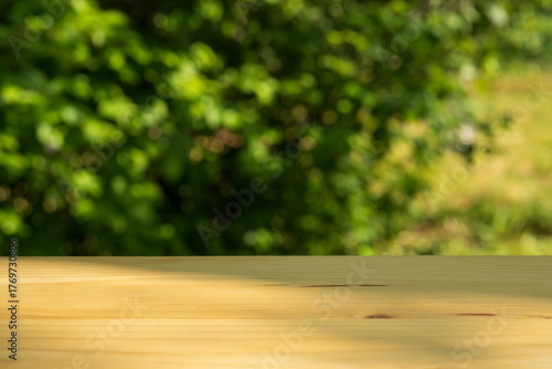 Wooden tabletop with blurred green foliage background
