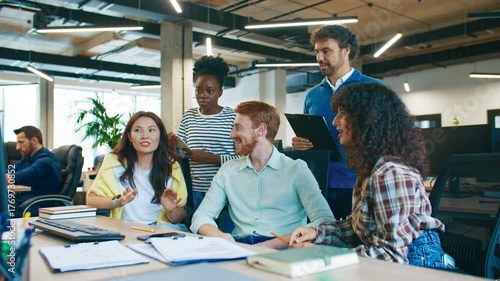 Focused coworkers discussing solution for computer problem at workplace. Men and women collaborating sharing ideas teamwork brainstorming to fix technical issue together in office setting.