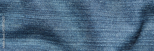 Close-up of blue denim fabric with detailed texture and woven pattern in soft light.