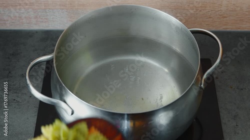 Add colorful farfalle pasta to salted boiling water to prepare a warm salad with chicken liver and celery