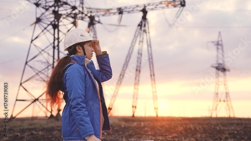 An engineer at a high-voltage power plant is working making an inspection at the sunset in the sky, electricity design, industry concept, modern business technology, an electrician with a project on