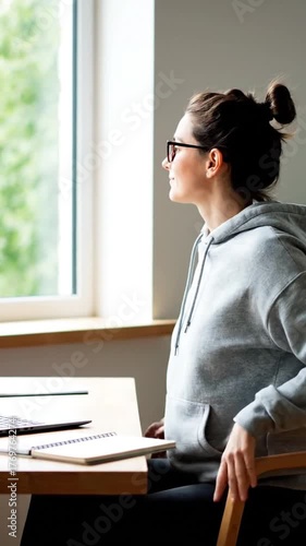 Woman working on laptop by window thinking indoors