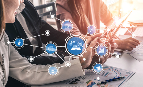 A dynamic scene of business professionals engaged in collaborative work, utilizing digital technology to analyze data and develop strategies in a modern office setting. Tessel