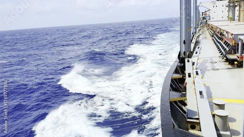 Cargo ship sailing in ocean with strong wind and waves crashing against hull — dynamic maritime scene showing the power of the sea and the resilience of ocean-going vessels in fresh wind conditions 12