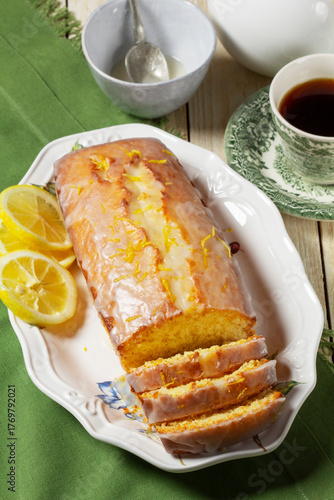 Aromatic lemon cake, covered with sugar icing and sprinkled with zest, served with tea.