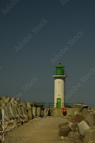 Green lighthouse on pier against clear blue sky