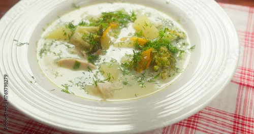 Broccoli soup pouring creamy vegetarian broccoli soup into a bowl garnished with fresh green dill top view.