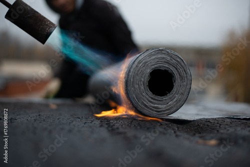 laying of a new bitumen roof on the roof. bitumen roll melting and adhesion, to protect the leakage. High quality photo
